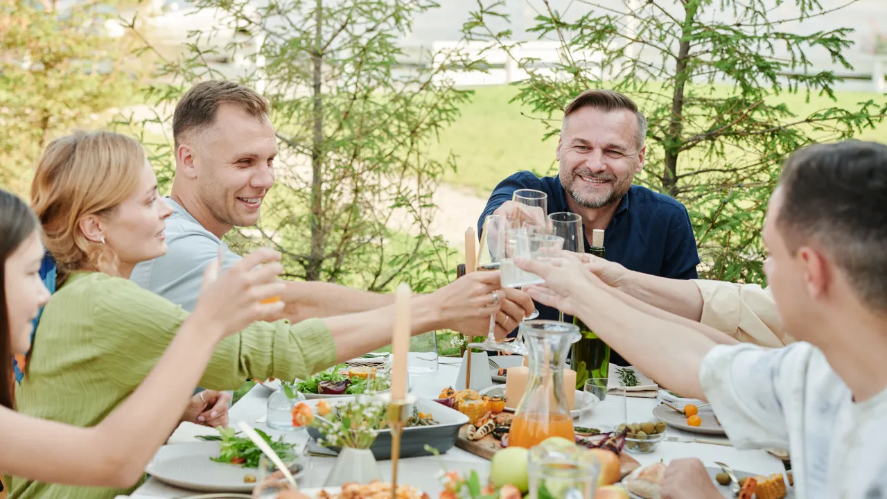 A group of adults shares a toast at a long outdoor table