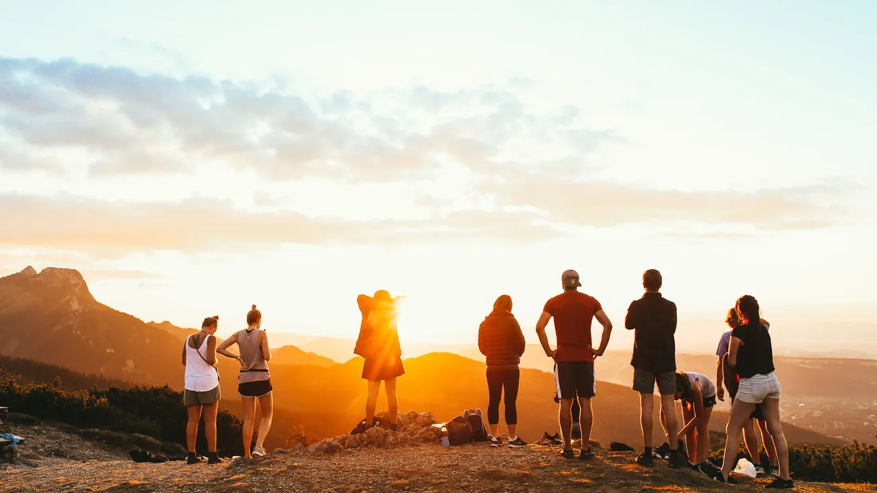A group of travellers looks across the landscape together at sunset
