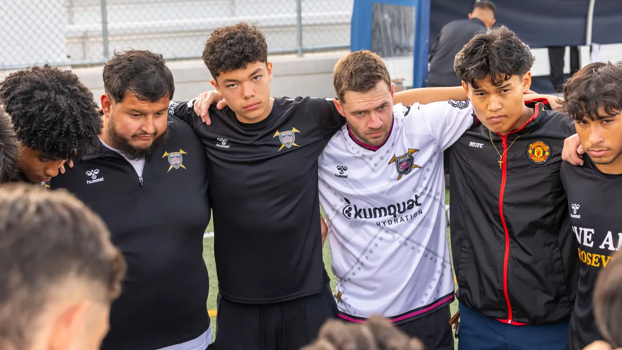 Football players gather in a team huddle on the pitch