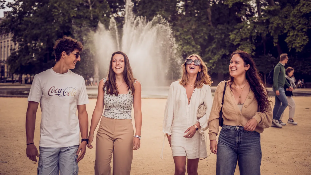 Young adults gather by a fountain during a visit to Brussels